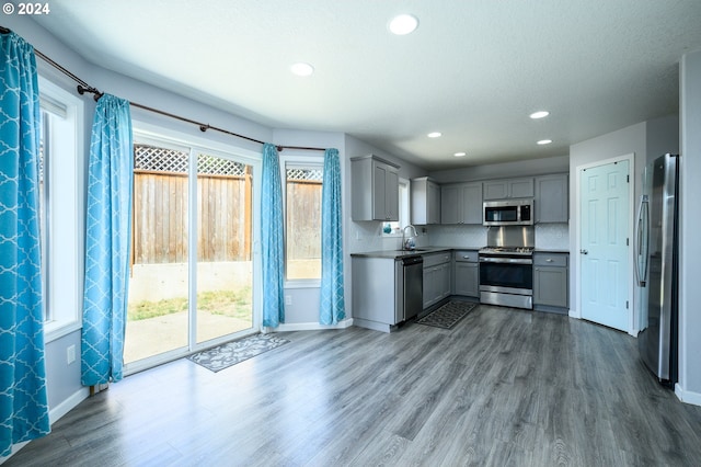 kitchen with appliances with stainless steel finishes, dark wood-style flooring, a sink, and gray cabinetry