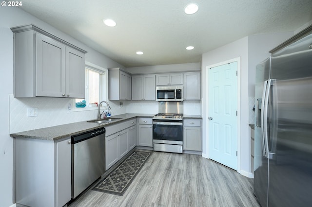 kitchen with stainless steel appliances, gray cabinets, and a sink