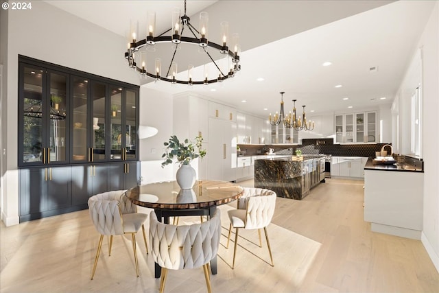 dining space with a notable chandelier, sink, and light wood-type flooring