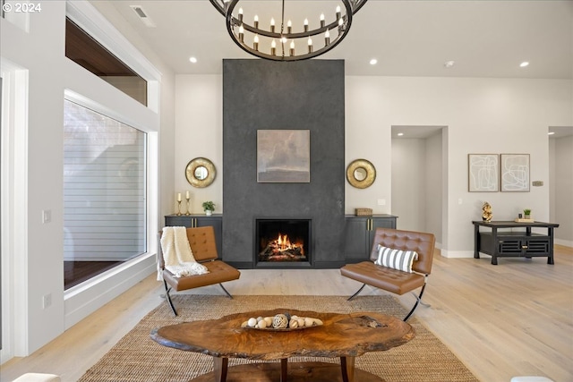 sitting room with a large fireplace, an inviting chandelier, and light hardwood / wood-style flooring