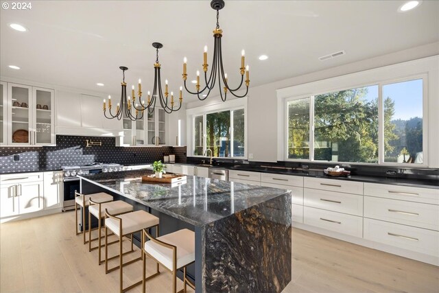 living area with light wood-type flooring, an inviting chandelier, and a fireplace