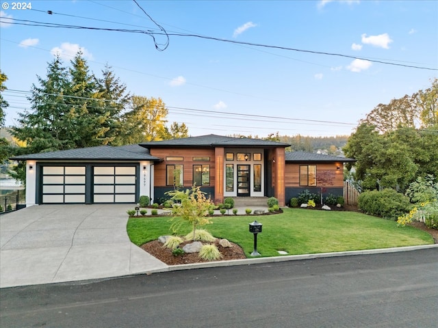 prairie-style house with a garage, driveway, and a front yard