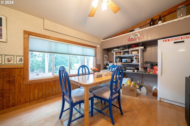 dining area with lofted ceiling, hardwood / wood-style floors, ceiling fan, and wooden walls