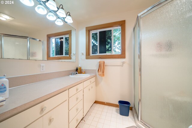 bathroom featuring vanity, a healthy amount of sunlight, tile patterned floors, and a shower with door