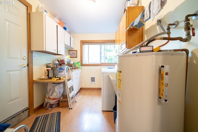 laundry room featuring washer and dryer, gas water heater, cabinets, and light wood-type flooring