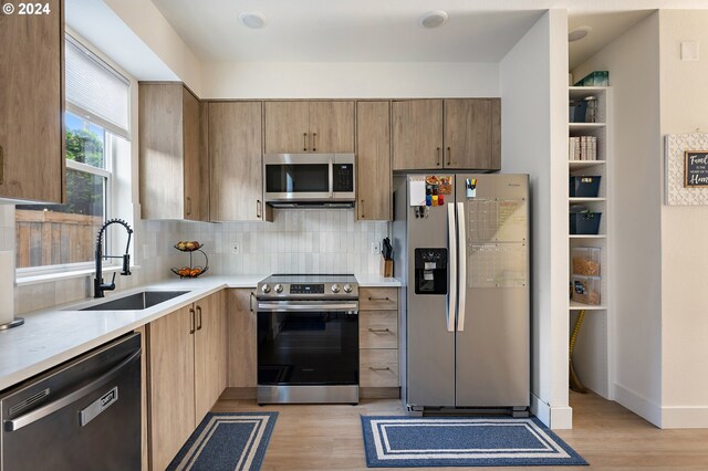 kitchen with light hardwood / wood-style flooring, stainless steel appliances, sink, and backsplash