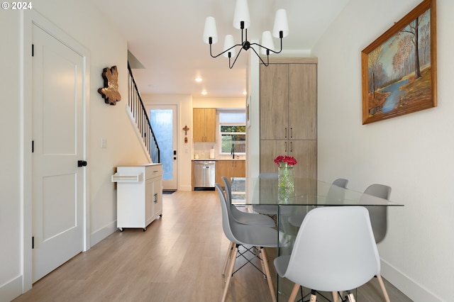 dining space featuring sink, light hardwood / wood-style floors, and a chandelier