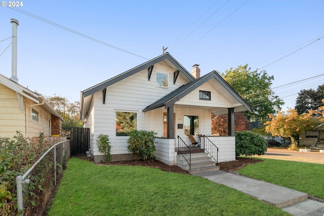 bungalow featuring covered porch and a front yard