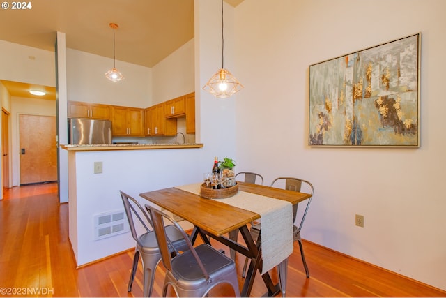 dining area featuring sink, a high ceiling, and light wood-type flooring