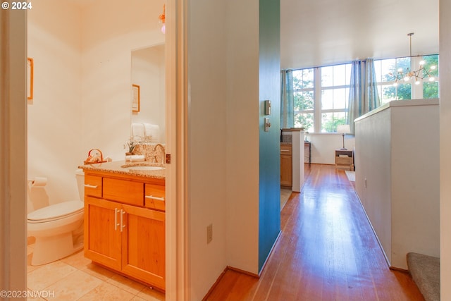 corridor with sink, a notable chandelier, and light wood-type flooring