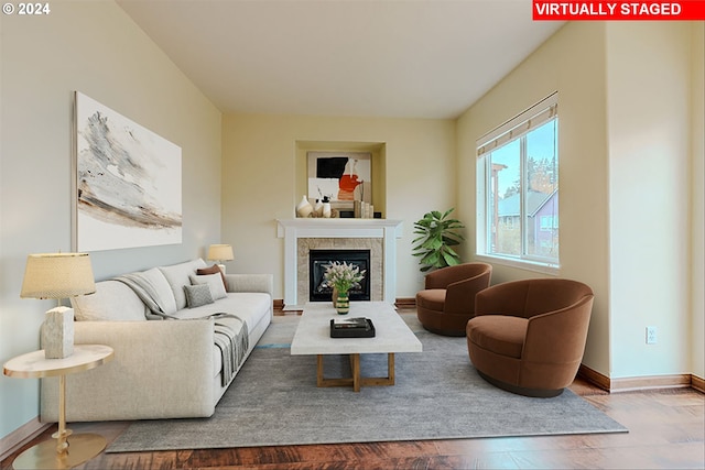 living room with a tiled fireplace and hardwood / wood-style flooring