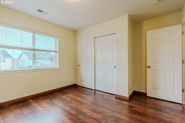 unfurnished bedroom with dark hardwood / wood-style flooring and a closet