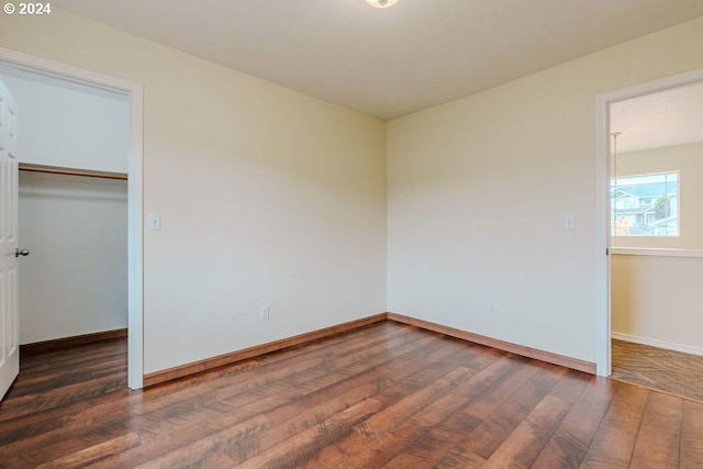 unfurnished bedroom featuring a spacious closet, a closet, and dark hardwood / wood-style flooring