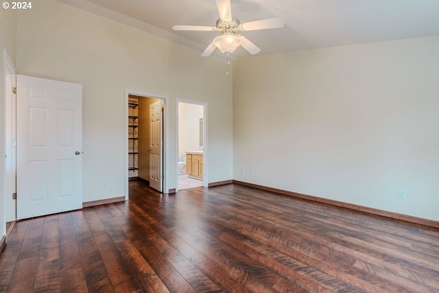 unfurnished bedroom featuring dark hardwood / wood-style flooring, ensuite bathroom, high vaulted ceiling, ceiling fan, and a walk in closet