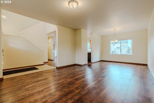 interior space featuring dark hardwood / wood-style flooring, a textured ceiling, and a notable chandelier