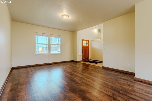 empty room featuring dark wood-type flooring and a textured ceiling