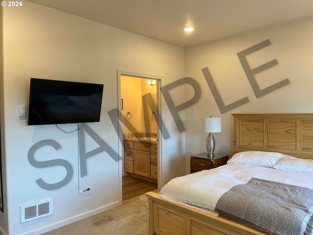 bedroom featuring ensuite bathroom and light colored carpet