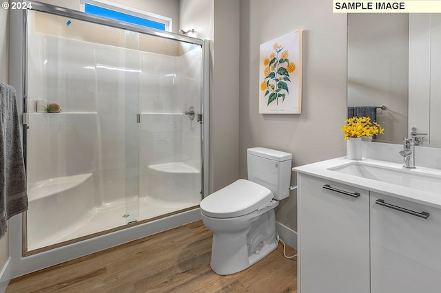 bathroom featuring wood-type flooring, an enclosed shower, vanity, and toilet