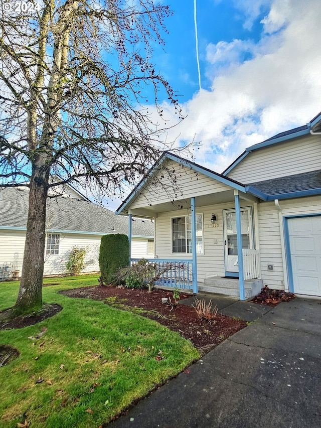 view of front of house featuring covered porch, a front yard, and a garage