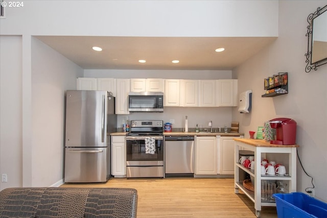 kitchen with white cabinets, sink, light wood-type flooring, and stainless steel appliances