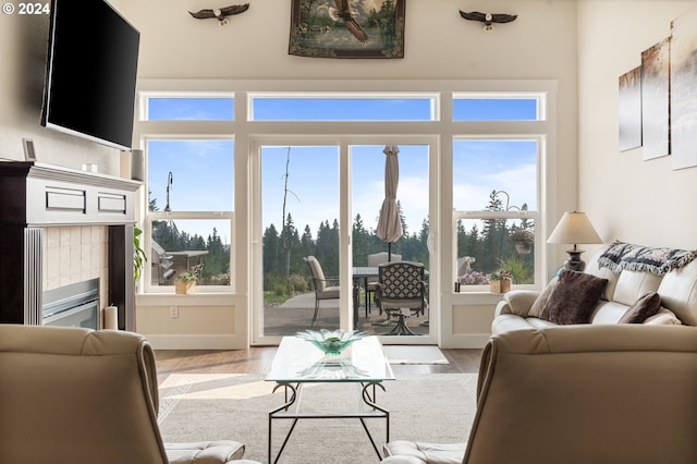 living room featuring a wealth of natural light, a tiled fireplace, and light hardwood / wood-style floors