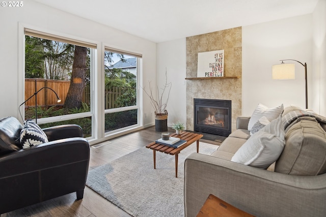 living room featuring a tiled fireplace and hardwood / wood-style floors