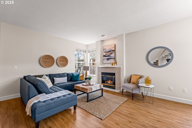 living room featuring hardwood / wood-style flooring, a tile fireplace, and a textured ceiling