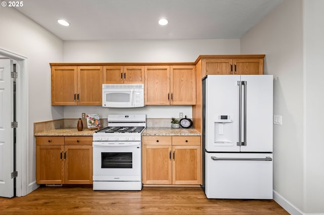 kitchen featuring light stone counters, white appliances, and hardwood / wood-style flooring