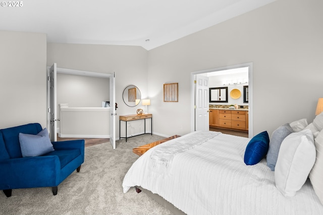 bedroom featuring lofted ceiling, connected bathroom, and light colored carpet