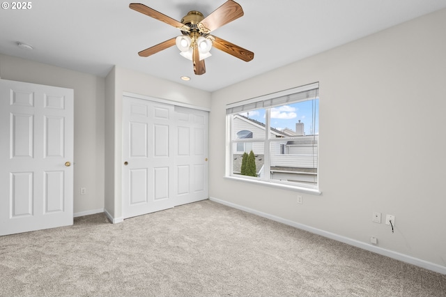 unfurnished bedroom featuring ceiling fan, light colored carpet, and a closet