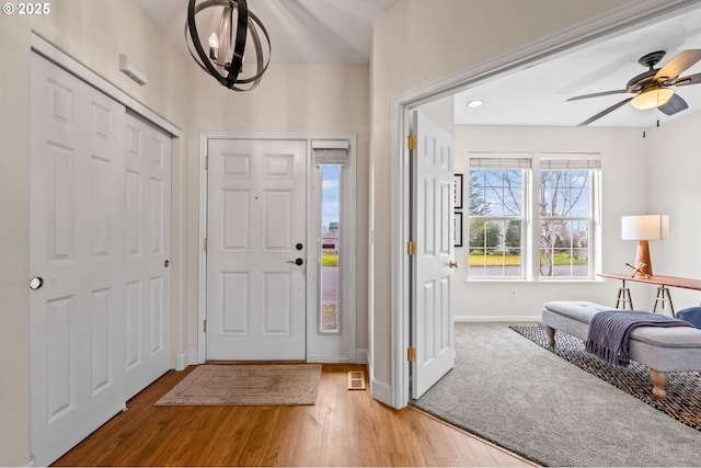 foyer entrance with ceiling fan with notable chandelier and hardwood / wood-style floors