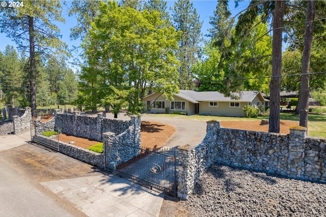 ranch-style house featuring a fenced front yard, curved driveway, and a gate