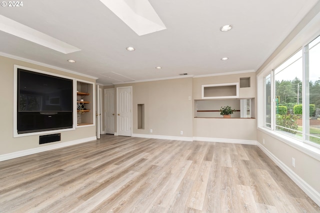 unfurnished living room with ornamental molding, a skylight, and light wood-style floors