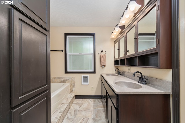 bathroom featuring a bath, a textured ceiling, baseboards, and a sink