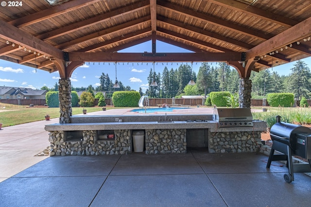 view of patio / terrace featuring outdoor dry bar, exterior kitchen, grilling area, and a fenced backyard