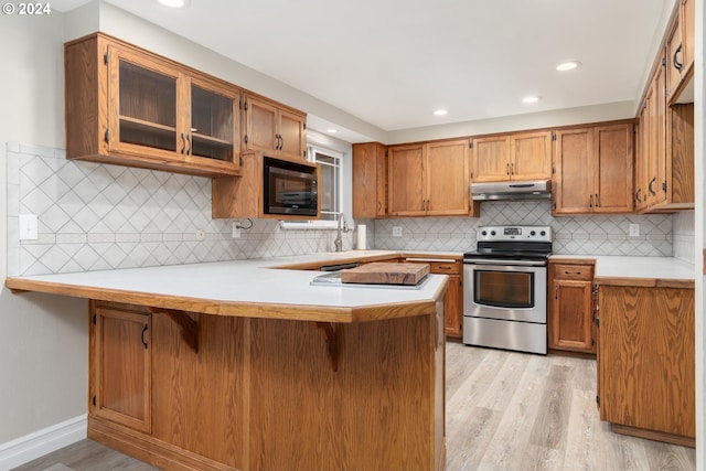 kitchen featuring black microwave, under cabinet range hood, a peninsula, stainless steel range with electric cooktop, and light countertops