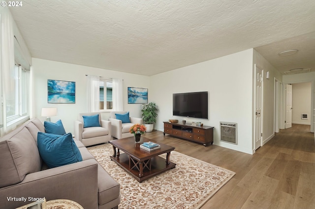 living room with hardwood / wood-style floors, a textured ceiling, and heating unit