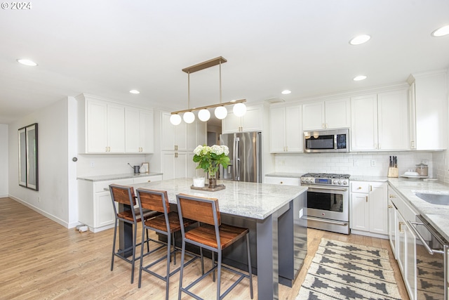 kitchen with white cabinets, decorative light fixtures, light hardwood / wood-style flooring, stainless steel appliances, and light stone countertops