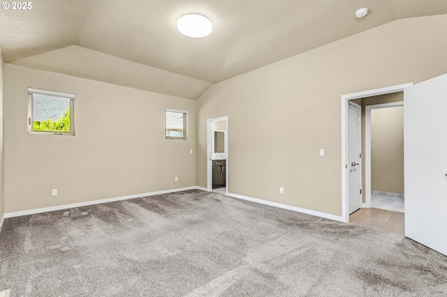 carpeted spare room featuring vaulted ceiling, baseboards, and a smoke detector