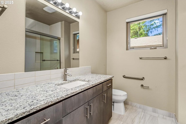bathroom with a shower stall, vanity, toilet, marble finish flooring, and baseboards