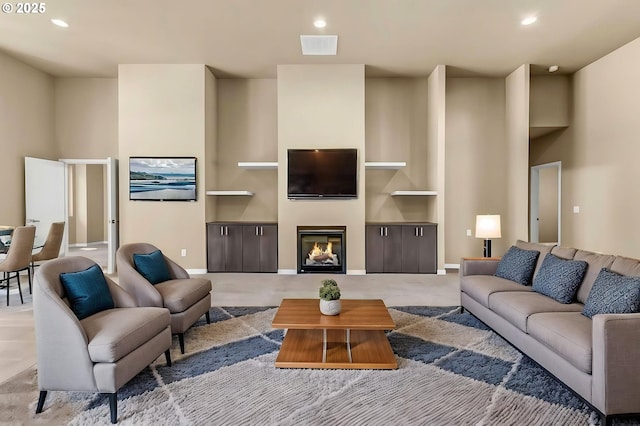 living area with recessed lighting, a glass covered fireplace, and baseboards