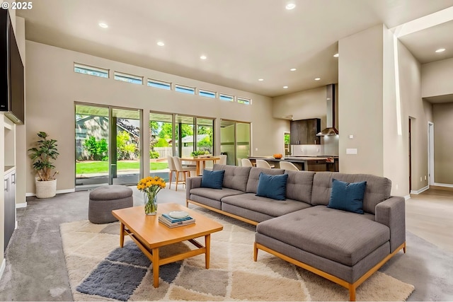 living room featuring a towering ceiling, recessed lighting, baseboards, and carpet floors