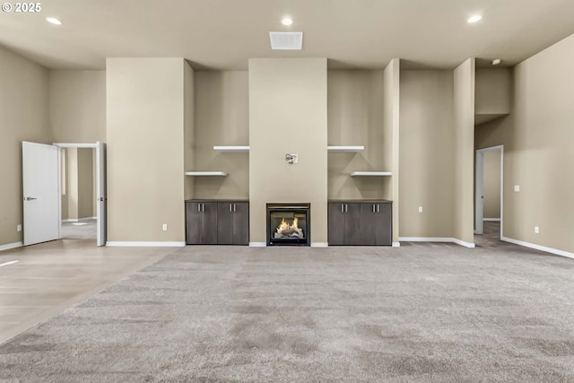 unfurnished living room with carpet floors, a high ceiling, recessed lighting, baseboards, and built in features