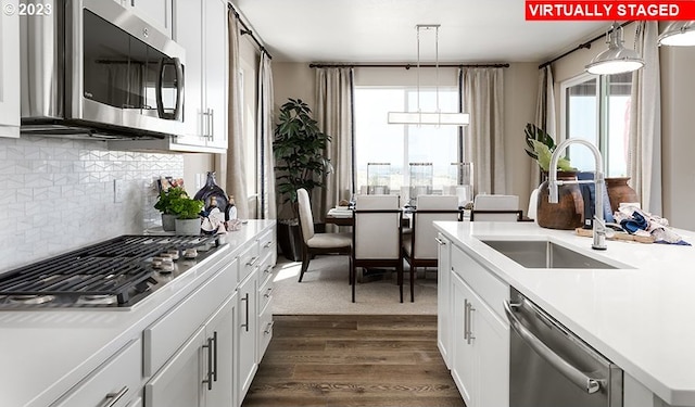 kitchen featuring appliances with stainless steel finishes, backsplash, sink, dark hardwood / wood-style flooring, and hanging light fixtures