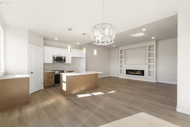 kitchen featuring white cabinets, open floor plan, a kitchen island with sink, stainless steel appliances, and light countertops