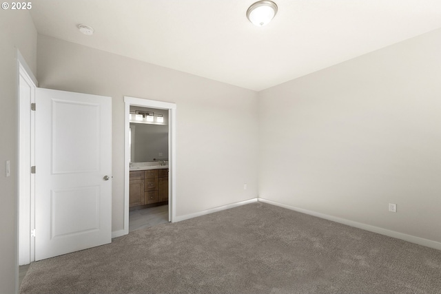 unfurnished bedroom featuring ensuite bath, baseboards, and carpet flooring