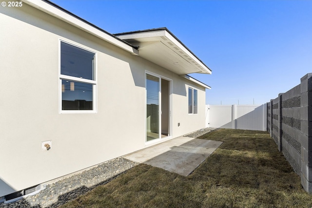 rear view of property with a fenced backyard, a lawn, a patio, and stucco siding