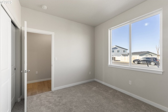 unfurnished bedroom featuring carpet, baseboards, and a closet