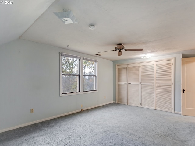 unfurnished bedroom featuring ceiling fan, lofted ceiling, carpet flooring, and a closet