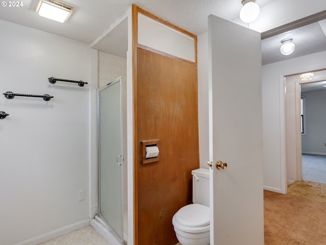 bathroom with a shower with shower door and toilet